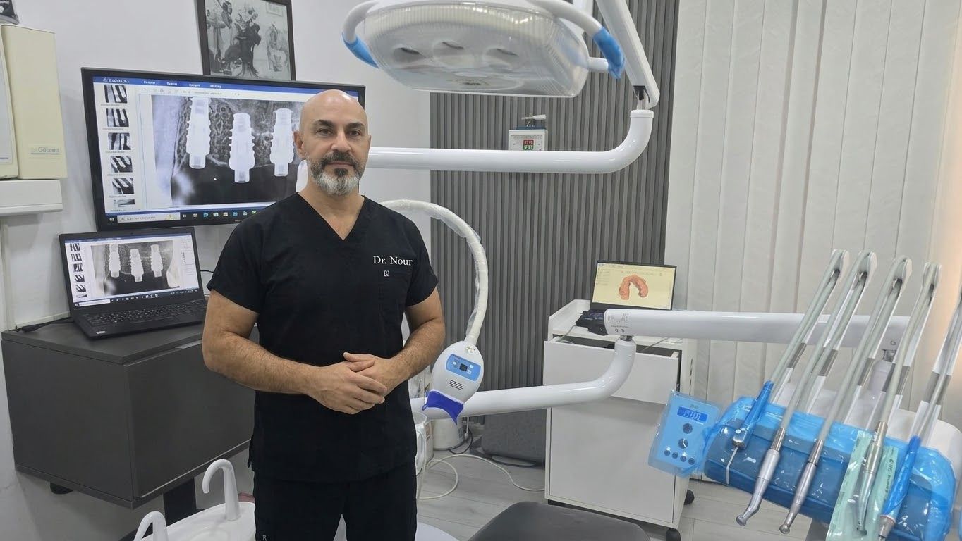 Dr. Nour Khattab Badreddine in the treatment room, with implant radiographs on the screens behind him