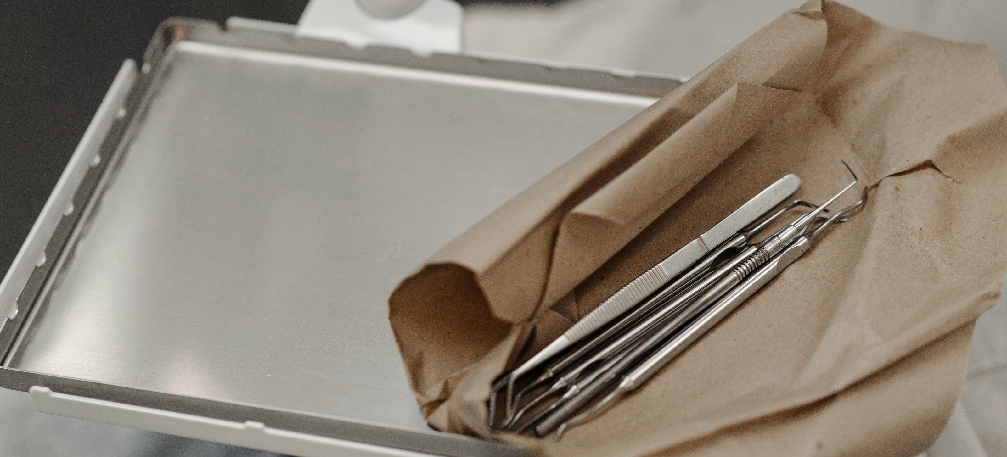 Dental instruments sealed in sterilisation paper on a steel tray